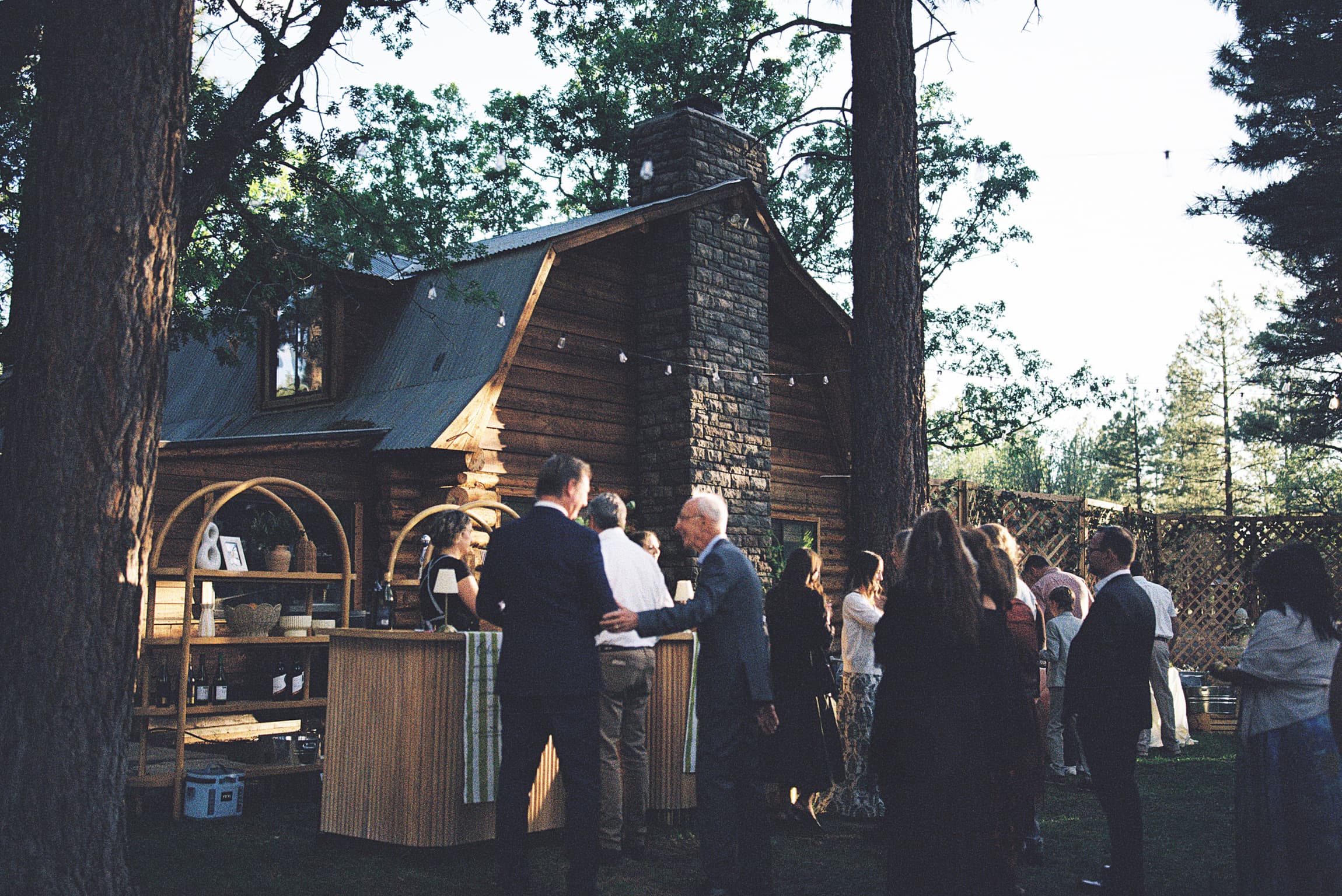 Guests gathered at dusk around a rustic log cabin venue in the Arizona White Mountains